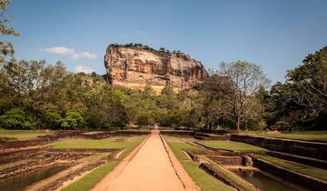 Majestic rock formation with lush greenery and ancient ruins.