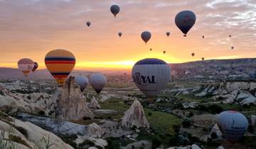 Hot air balloons flying over Cappadocia during sunrise.