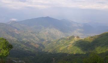 Landscape of lush green mountains under a cloudy sky.