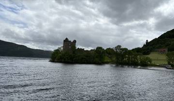 A historic castle by a lake surrounded by lush greenery.