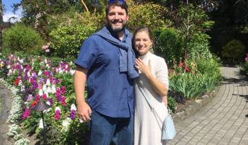 Couple standing in a colorful garden on a sunny day.
