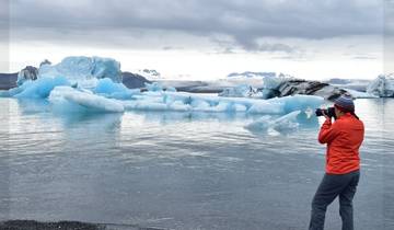 Person photographing icebergs on a glacial lake.