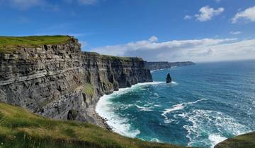 Dramatic cliffs by the ocean under a blue sky.