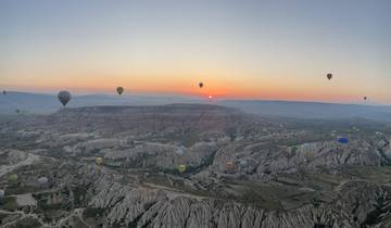 Hot air balloons over a valley at sunrise.