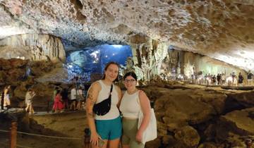 Two people standing in a cave with a scenic backdrop.
