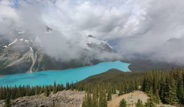 A serene lake surrounded by mountains with mist and clouds.