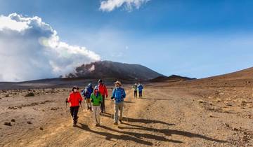 Group of hikers walking toward a towering mountain under a sunny sky.