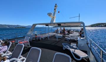 Deck of a yacht with lounge chairs under a clear blue sky.
