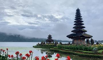 Beautiful lakeside temple surrounded by mountains and flowers.