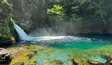 A waterfall in a lush, green, rocky landscape.
