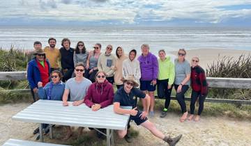 Group of people posing by the seashore with cloudy sky.