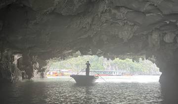 Person on a boat emerging from a cave with distant boats visible.