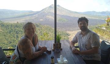 Two people sitting at a table with a scenic view of a volcano.