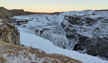 Frozen waterfall surrounded by snow-covered cliffs.