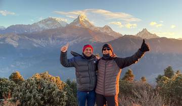 Two people posing with mountains in the background during sunrise.