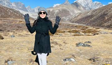 Woman with raised arms in a mountainous valley setting.