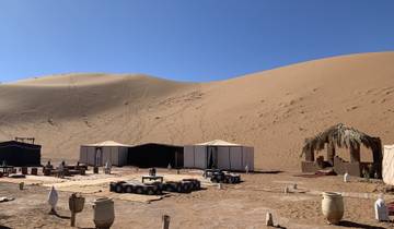 A desert campsite with tents and sand dunes.