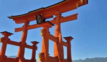 Famous red torii gate by the water with visitors.