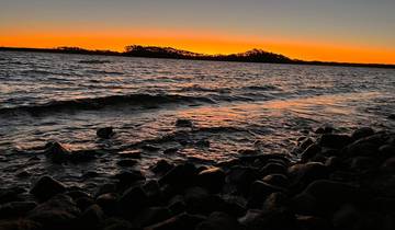 Rocky shoreline at sunset with silhouette-style lighting.
