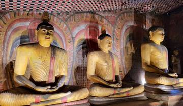 Three ancient statues of Buddha in a cave with ornate wall art.