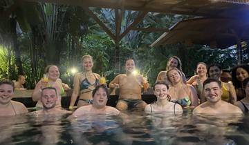 A group of people enjoying a hot spring pool in a lush, tropical setting.