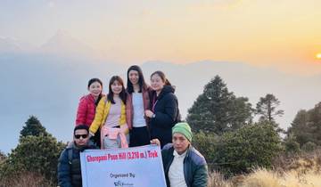 Group holding a trek sign with mountain range in the background.