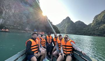 Group of people on a boat wearing life jackets in a scenic setting.