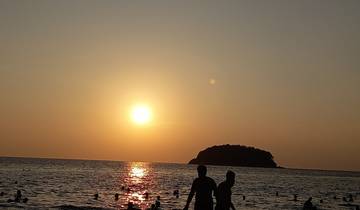 Silhouettes of people against a sunset at the beach.
