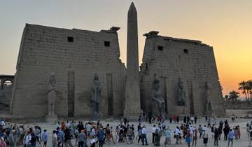 Large ancient temple entrance with an obelisk and many tourists.