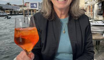 Person holding a drink by a canal with boats.