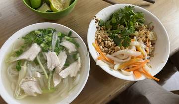 Two bowls of traditional Vietnamese food with herbs and vegetables.