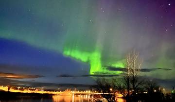 Northern lights vivid in the night sky with some water reflections.
