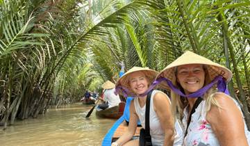 Tourists paddling through a waterway lined with palm trees.