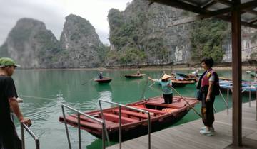 People rowing boats in a picturesque bay with rocky cliffs.
