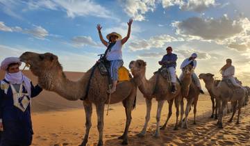 People riding camels in the desert.
