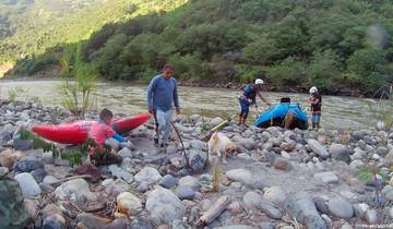 People preparing kayaks by a river.