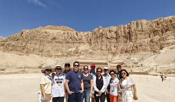 Group of people posing in front of a historical site in the desert.