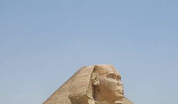The Sphinx in front of the Pyramid of Khafre in Giza under a clear sky.