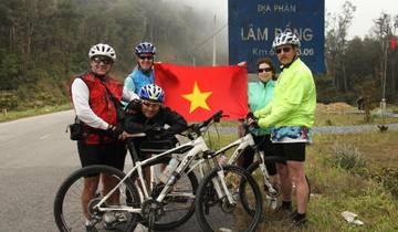 Cyclists posing with a flag in front of a road sign.
