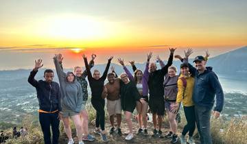 Group of people with raised arms at sunrise on a hill.