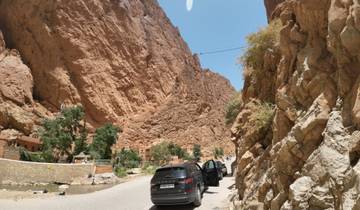 Rocky canyon in a desert climate with cars parked by the road.