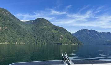 Scenic view of mountains and a lake with forested slopes and blue sky.