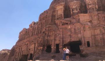 Ancient structure carved into red rock with two people posing.