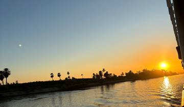 Sunset view from a river with silhouettes of trees.