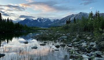 A serene landscape reflecting mountains on still water at sunset.