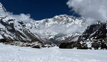 Snowy mountain range with clouds partially covering peaks.
