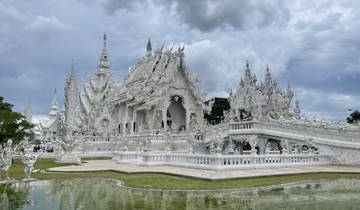 Intricately detailed white temple reflected in a pond.