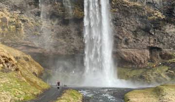 Waterfall flowing over rocky terrain into a valley.