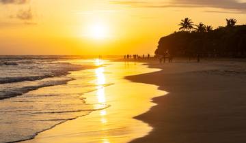 A beautiful sunset on a sandy beach with silhouettes of people.