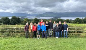 Group of people posing with a scenic lake and mountain backdrop.